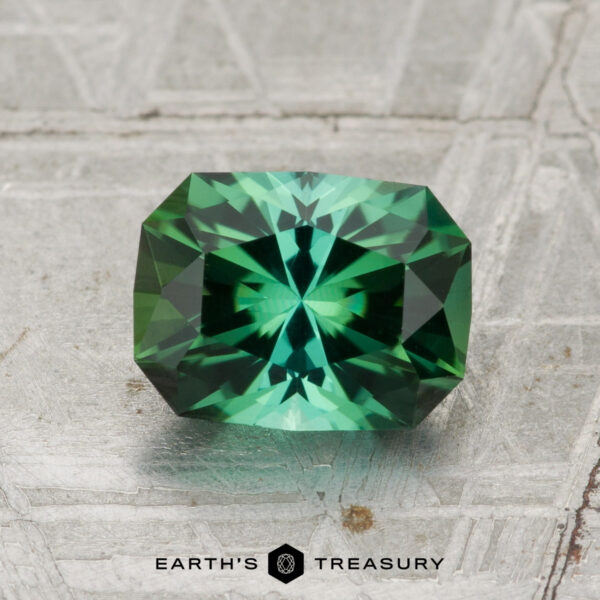 1.45-Carat Tourmaline A 1.45-carat rectangular green tourmaline with intricate facets is shown on a textured background, with "EARTH'S TREASURY" written below.