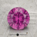 A round, faceted 2.50-carat pastel pyrope garnet is displayed on a textured surface with "EARTH'S TREASURY" written below.