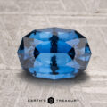A 2.63-carat heated sapphire is displayed on a textured light gray surface with the "Earth's Treasury" logo beneath it.