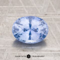 A 2.14-carat Ceylon sapphire, oval-cut and light blue, is displayed on a textured surface with the "Earth's Treasury" logo and text at the bottom.