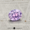 A round brilliant-cut 0.78-carat Montana Sapphire with a purple hue is displayed on a textured metallic surface. The "EARTH'S TREASURY" logo is shown at the bottom.