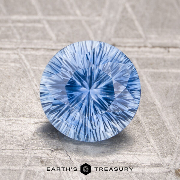 1.85-Carat Sky Blue Madagascar Sapphire (Unheated) A 1.85-carat unheated Ceylon sapphire, round brilliant-cut, is showcased on a textured light surface with the "Earth's Treasury" logo and text below.