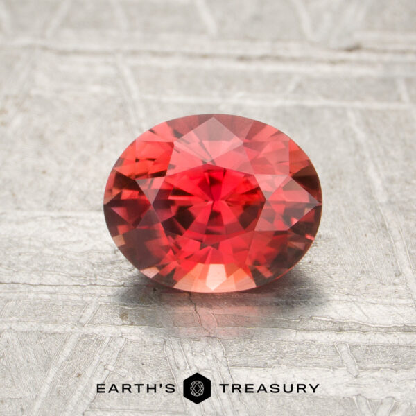 1.11-Carat Sapphire (Heated) A 1.11-carat heated oval-cut sapphire with intricate facets rests on a textured gray surface, with "Earth's Treasury" displayed below.