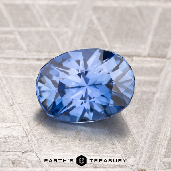 1.67-Carat Ceylon Sapphire (Heated) A 1.67-carat heated Ceylon sapphire is displayed on a textured metallic surface, with the text "EARTH'S TREASURY" appearing at the bottom of the image.