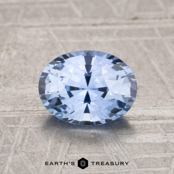 1.48-Carat Sky Blue Ceylon Sapphire 1.48-Carat Ceylon Sapphire, oval-cut blue gemstone, showcased on a textured beige surface with the "Earth's Treasury" logo at the bottom.