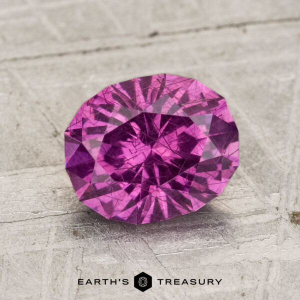 2.01-Carat Pastel Pyrope Garnet A 2.01-carat pastel pyrope garnet gemstone sits on a textured, light gray surface with "EARTH'S TREASURY" displayed at the bottom.