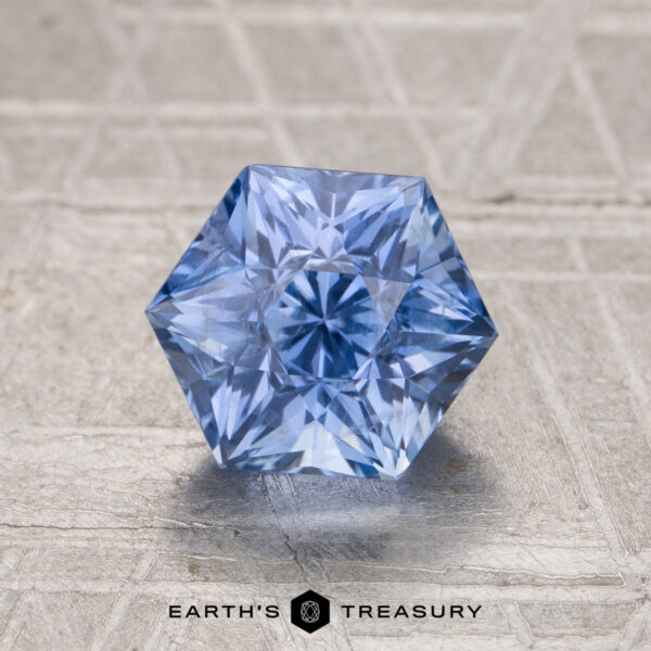 2.06-Carat Ceylon Sapphire A 2.06-carat Ceylon sapphire with hexagonal facets is displayed on a textured, light surface, with "Earth's Treasury" written below.