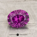 A 1.92-carat Pastel Pyrope Garnet, oval-cut and faceted, displayed on a textured surface with "Earth's Treasury" at the bottom.