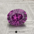 A 1.92-carat pastel pyrope garnet with an oval cut is displayed on a gray textured surface, featuring the "EARTH'S TREASURY" text at the bottom.