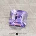 A 1.66-carat, square-cut Ceylon sapphire with step facets and a light purple hue is displayed on a textured gray surface above the words "EARTH'S TREASURY.