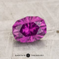 A 1.83-carat Pastel Pyrope Garnet, faceted in an oval shape, rests on a textured light surface with "EARTH'S TREASURY" below it.