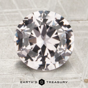 A 3.48-carat round brilliant-cut sapphire is displayed on a light, patterned surface with the text "Earth's Treasury" and a logo beneath it.