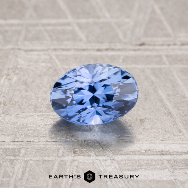 1.03-Carat Ceylon Sapphire (Heated) A 1.03-carat heated Ceylon sapphire, faceted in an oval shape, is displayed on a textured light surface with "EARTH'S TREASURY" beneath the gemstone.