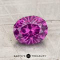 A 1.75-carat pastel pyrope garnet with an oval cut is displayed on a textured surface. The "Earth's Treasury" logo and name are visible at the bottom of the image.