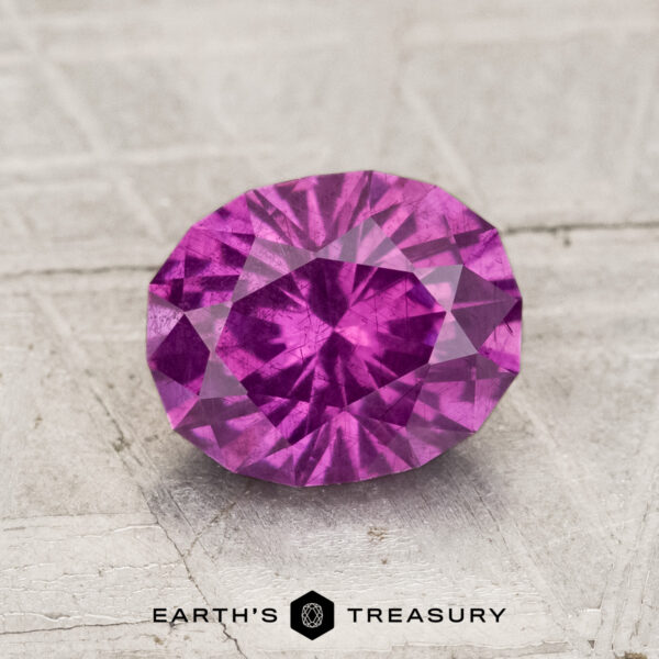 1.75-Carat Pastel Pyrope Garnet A 1.75-carat pastel pyrope garnet with an oval cut is displayed on a textured surface. The "Earth's Treasury" logo and name are visible at the bottom of the image.