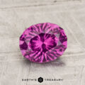 A 1.71-carat pastel Pyrope Garnet with visible inclusions rests on a textured light gray surface. The text "EARTH'S TREASURY" appears at the bottom.