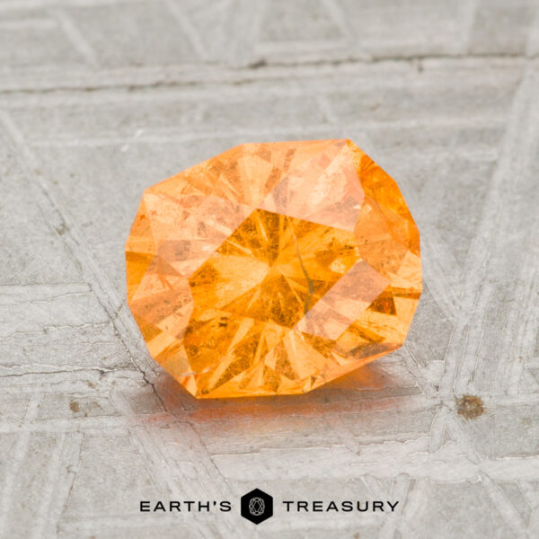 1.96-Carat Spessartine Garnet 1.96-carat Spessartine Garnet displayed on a textured gray surface, with "Earth's Treasury" text at the bottom.
