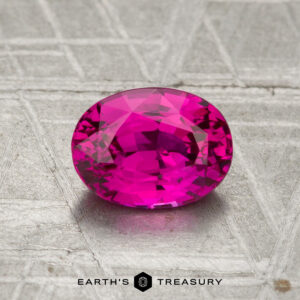 A 1.29-carat Vietnamese Ruby (heated), faceted oval and pink, rests on a textured metallic surface with "Earth's Treasury" below.