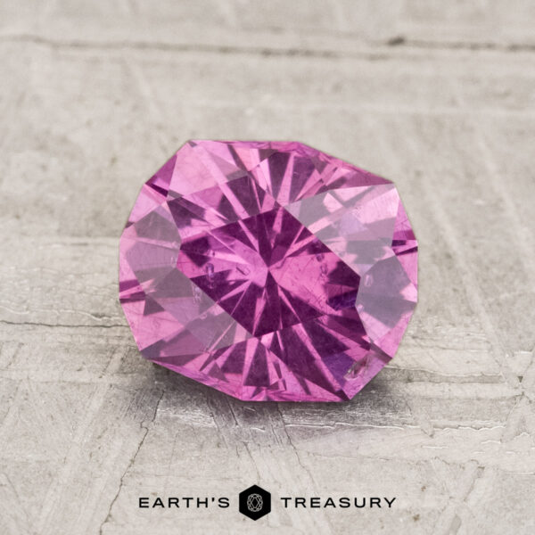 1.71-Carat Pastel Pyrope Garnet A round, faceted 1.71-carat pastel pyrope garnet is displayed on a light textured surface, with the text "EARTH'S TREASURY" and a logo below it.
