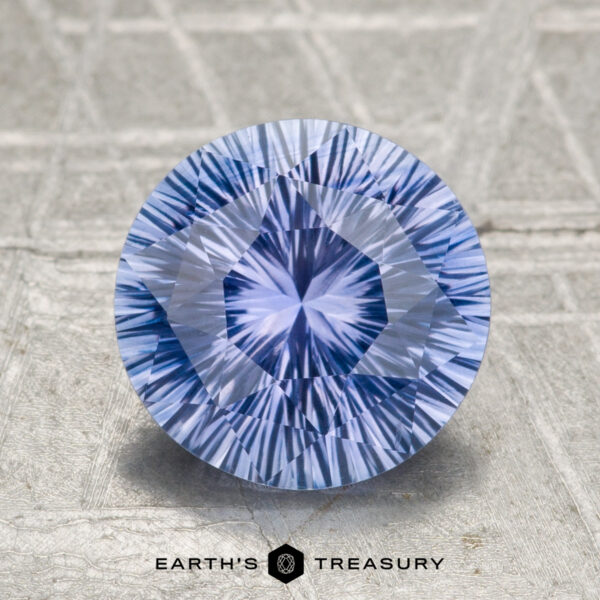 2.04-Carat Ceylon Sapphire (Heated) A 2.04-carat heated Ceylon sapphire, round and intricately faceted, is displayed on a textured surface with the "Earth’s Treasury" logo beneath it.