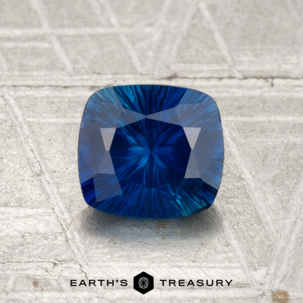 1.17-Carat Ceylon Sapphire (Heated) A 1.17-carat heated Ceylon sapphire with a cushion cut is displayed on a textured metallic surface, featuring the "EARTH'S TREASURY" logo and text at the bottom.