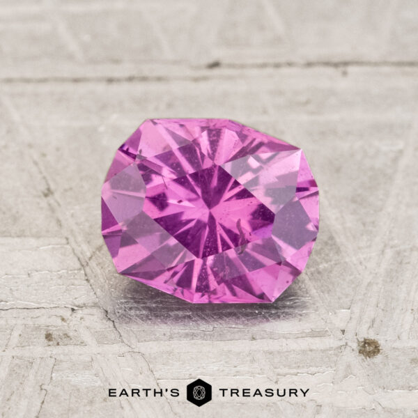 1.19-Carat Pastel Pyrope Garnet A 1.19-carat pastel pyrope garnet, round brilliant-cut, is displayed on a textured light surface with "EARTH'S TREASURY" at the bottom.