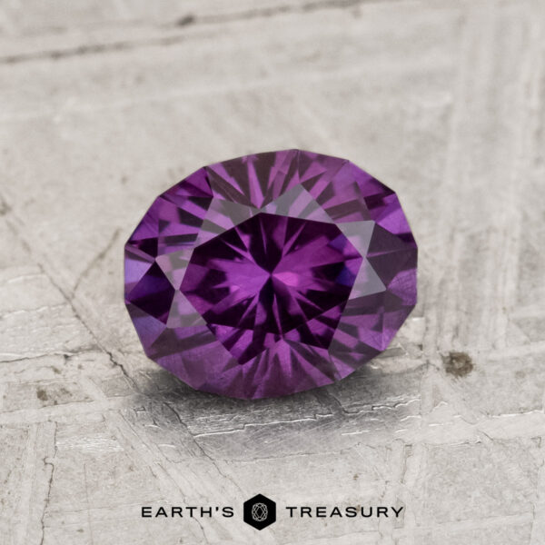 1.46-Carat Color-Change Garnet A 1.46-carat color-change garnet is displayed on a textured, light-colored surface with "EARTH'S TREASURY" written below.
