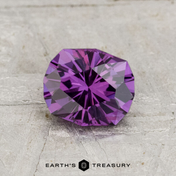 1.21-Carat Color-Change Garnet A 1.21-carat color-change garnet with a geometric cut rests on a textured light gray surface; the "Earth's Treasury" logo appears at the bottom.
