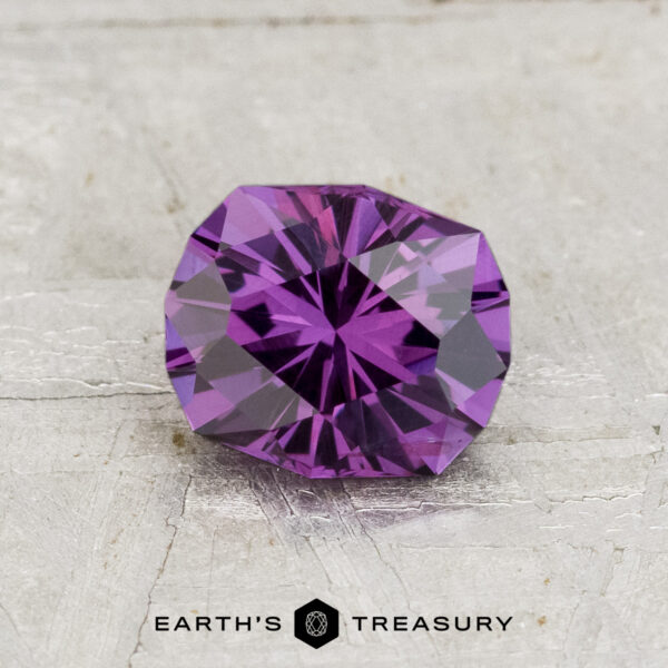 1.21-Carat Color-Change Garnet A faceted, round 1.21-carat color-change garnet gemstone rests on a textured light surface, with the "Earth's Treasury" logo and text at the bottom.