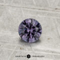 A 0.55-carat color-change garnet, expertly faceted and purple in hue, is displayed on a textured gray surface with the "Earth's Treasury" logo at the bottom.