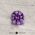 A 0.55-carat color-change garnet, round-cut, displayed on a textured light surface with "Earth's Treasury" at the bottom.