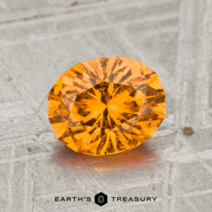 A 1.66-carat spessartine garnet, round brilliant-cut, is shown on a textured metallic surface with "EARTH'S TREASURY" beneath it.