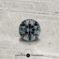 A 0.40-carat color-change garnet cut in a round, faceted shape is showcased on a light gray textured surface with the text "Earth's Treasury" at the bottom.