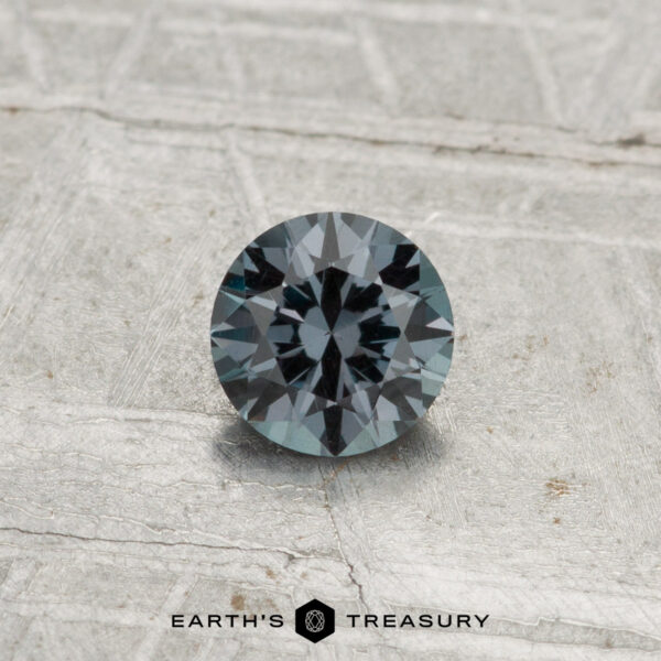 0.40-Carat Color-Change Garnet A 0.40-carat color-change garnet cut in a round, faceted shape is showcased on a light gray textured surface with the text "Earth's Treasury" at the bottom.