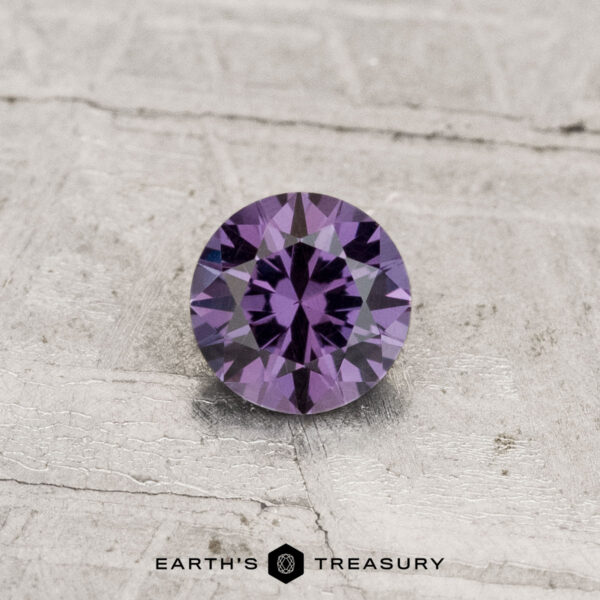 0.40-Carat Color-Change Garnet 0.40-carat color-change garnet, round brilliant-cut, displayed on a textured light gray surface with "Earth's Treasury" text at the bottom.