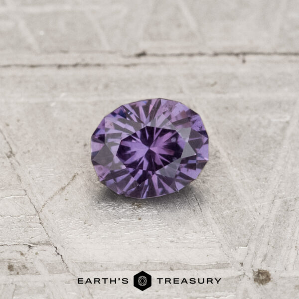 0.44-Carat Color-Change Garnet A round, faceted 0.44-carat color-change garnet is displayed on a textured, light-colored surface. The text "EARTH'S TREASURY" appears at the bottom of the image.
