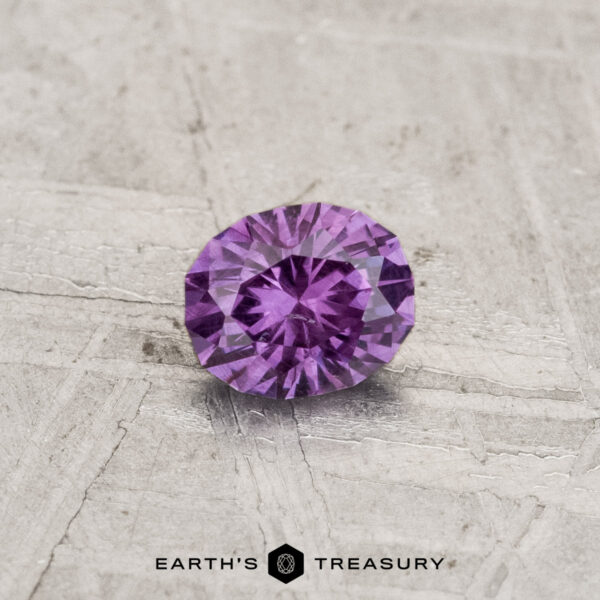 0.43-Carat Color-Change Garnet A 0.43-carat color-change garnet with a round cut is displayed on a textured light gray surface featuring "Earth's Treasury" branding at the bottom.