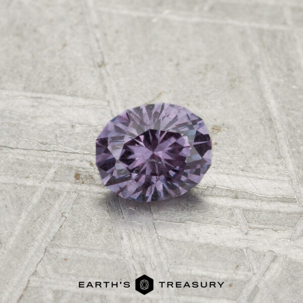 0.43-Carat Color-Change Garnet A round, faceted 0.43-carat color-change garnet sits on a textured gray surface, with "EARTH'S TREASURY" printed at the bottom.