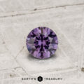A 0.42-carat color-change garnet, round-cut and purple, is displayed on a textured light gray surface with "Earth's Treasury" and a hexagon logo at the bottom.