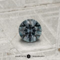 A round, faceted 0.42-carat color-change garnet sits on a textured metallic surface, with "EARTH'S TREASURY" displayed at the bottom.
