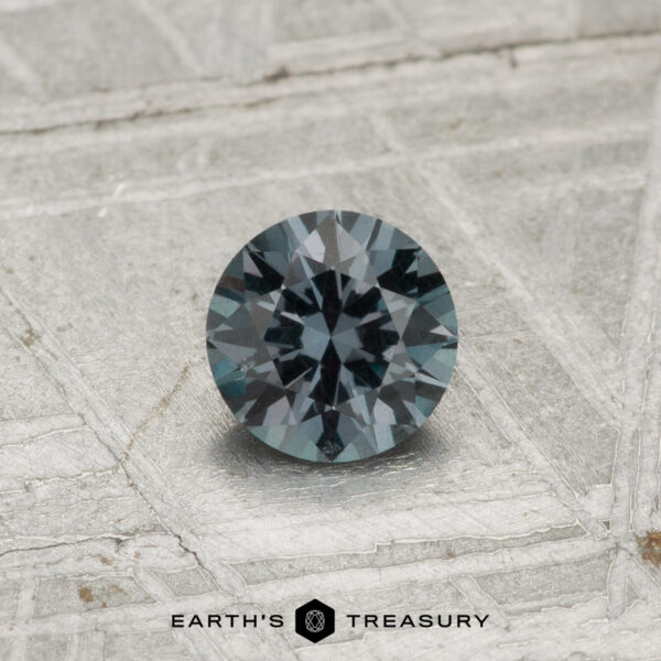 0.42-Carat Color-Change Garnet A round, faceted 0.42-carat color-change garnet sits on a textured metallic surface, with "EARTH'S TREASURY" displayed at the bottom.