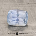 A 2.06-carat, faceted aqua blue to periwinkle unheated Montana sapphire rests on a textured gray surface, with "Earth's Treasury" displayed below it.