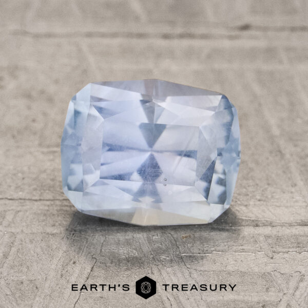 2.06-Carat Aqua Blue to Periwinkle Montana Sapphire (Unheated) A 2.06-carat, faceted aqua blue to periwinkle unheated Montana sapphire rests on a textured gray surface, with "Earth's Treasury" displayed below it.