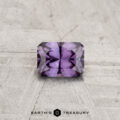 A rectangular, faceted 0.39-carat color-change garnet is displayed on a textured light gray surface featuring the "Earth's Treasury" logo and text at the bottom.