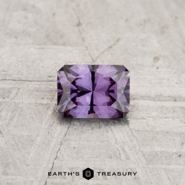 0.39-Carat Color-Change Garnet A rectangular, faceted 0.39-carat color-change garnet is displayed on a textured light gray surface featuring the "Earth's Treasury" logo and text at the bottom.