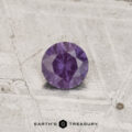 A 0.29-carat color-change garnet with a round cut is shown on a textured, light surface, with "EARTH'S TREASURY" displayed below.