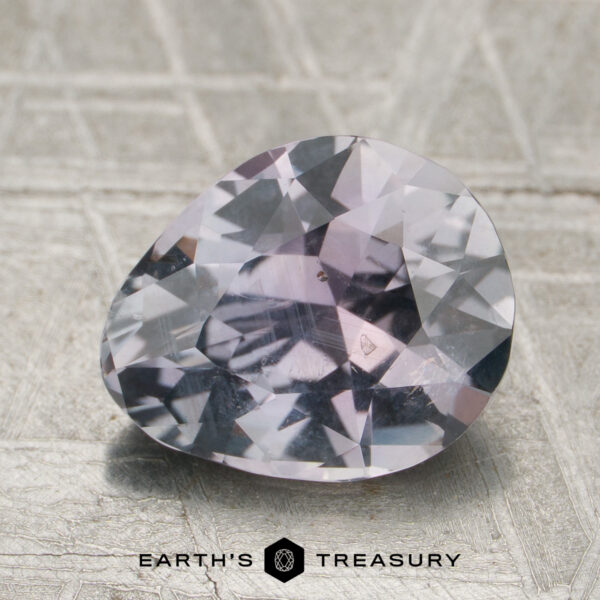 2.38-Carat Purplish Gray to Lilac Pink Montana Sapphire (Unheate A 2.38-carat purplish gray to lilac pink Montana sapphire (unheated) rests on a textured surface, with "EARTH'S TREASURY" and logo shown at the bottom.