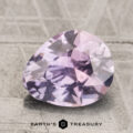A 2.38-carat purplish gray to lilac pink unheated Montana sapphire, faceted in an oval cut, rests on a textured surface with the "EARTH'S TREASURY" logo below.