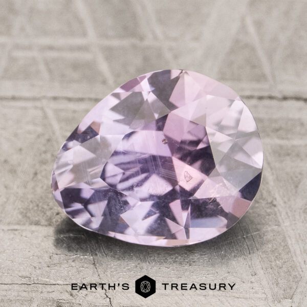 2.38-Carat Purplish Gray to Lilac Pink Montana Sapphire (Unheate A 2.38-carat purplish gray to lilac pink unheated Montana sapphire, faceted in an oval cut, rests on a textured surface with the "EARTH'S TREASURY" logo below.