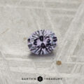 A 0.28-carat color-change garnet, round and faceted, is displayed on a textured gray surface with "Earth's Treasury" at the bottom.
